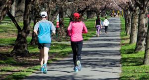 people running and walking in a park following the advice from Celia Monk therapy. Becoming active after covid.